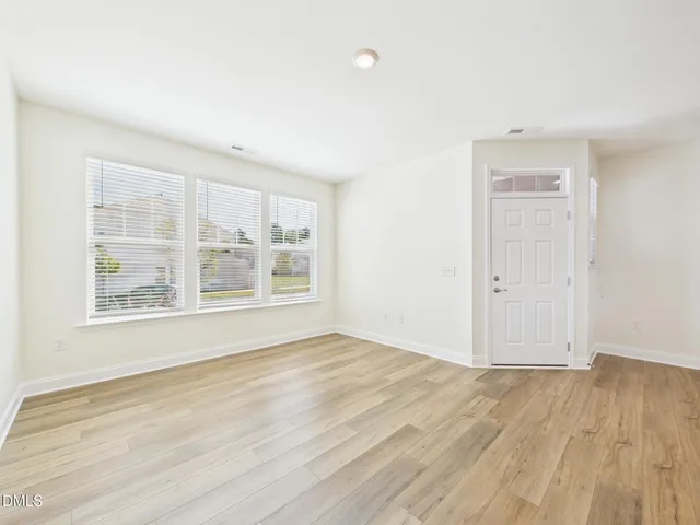 a view of an empty room with wooden floor and closet