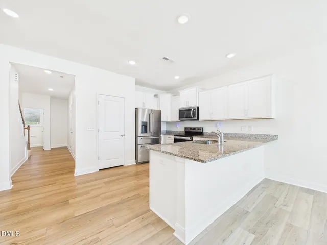 a kitchen with granite countertop a stove top oven a sink dishwasher and a refrigerator