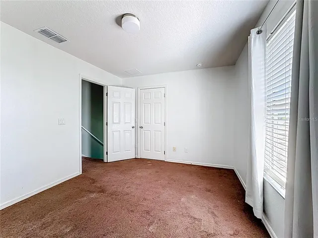 a view of an empty room and a ceiling fan & windows