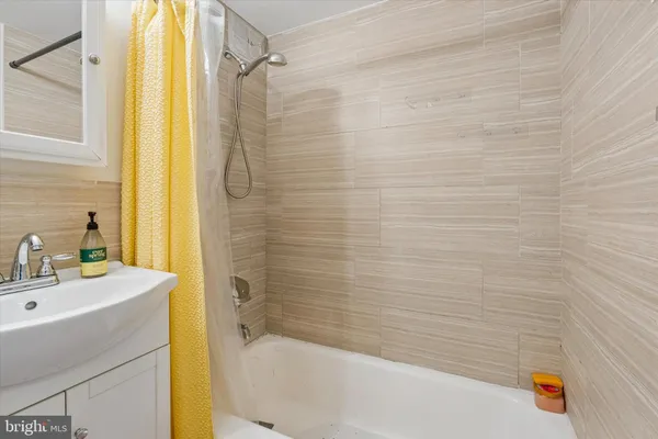 a bathroom with a tub sink vanity and a shower