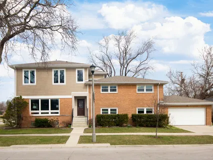 a front view of a house with a garden and trees