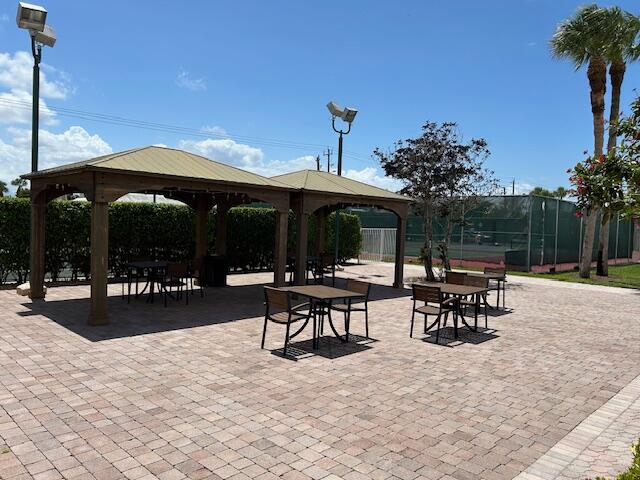 221 Lake Meryl Drive West Palm Beach, FL 33411 - Photo 28 of 31 a view of a patio with a table and chairs under an umbrella