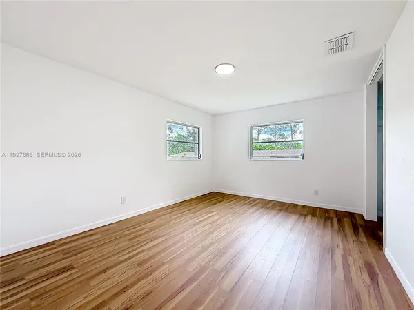 an empty room with wooden floor and windows