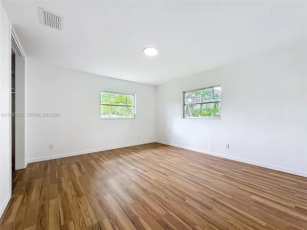 an empty room with wooden floor and windows