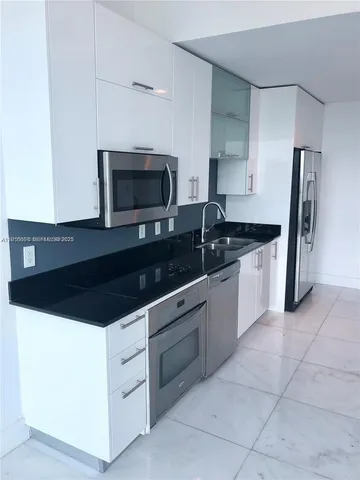 a kitchen with stainless steel appliances a sink a stove a microwave and a refrigerator