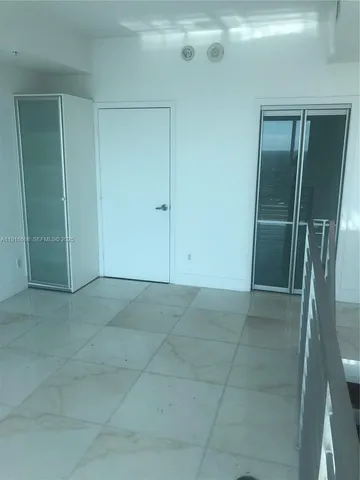 a view of an empty room with wooden floor and a bathroom