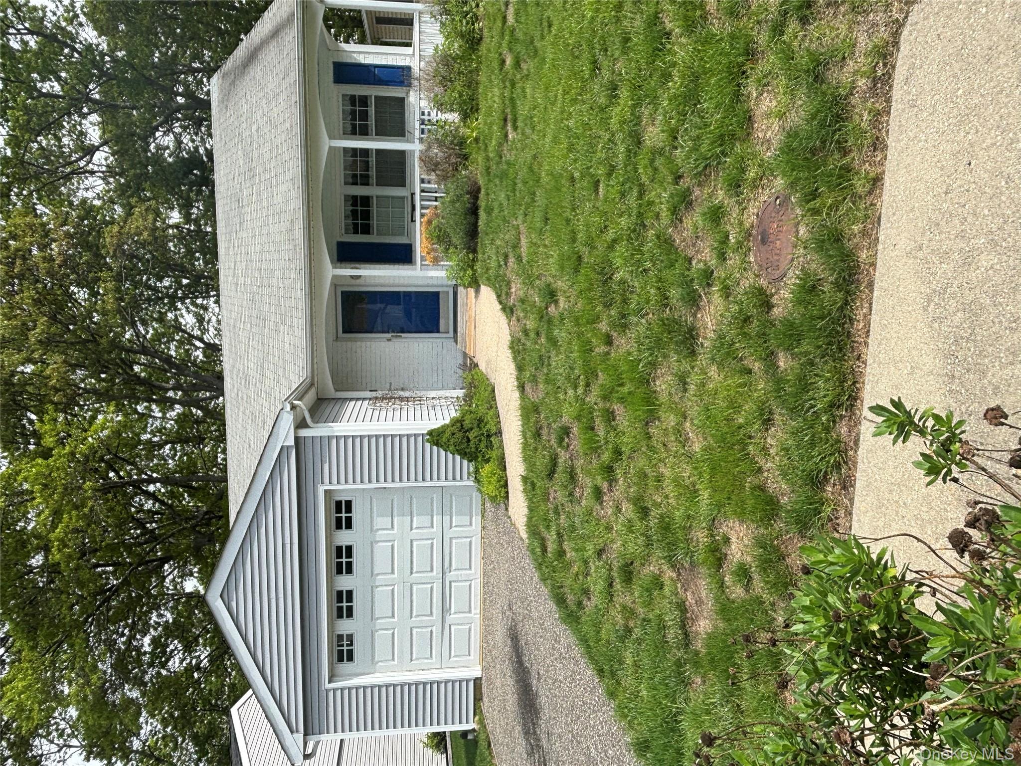 Ranch-style home featuring driveway, covered porch, a front yard, and an attached garage
