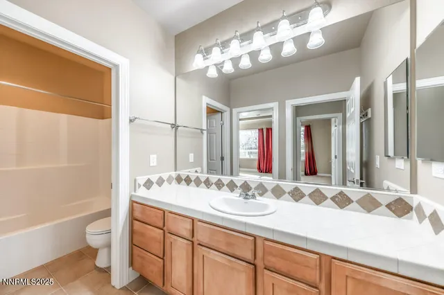 a bathroom with a sink a toilet a large mirror and shower