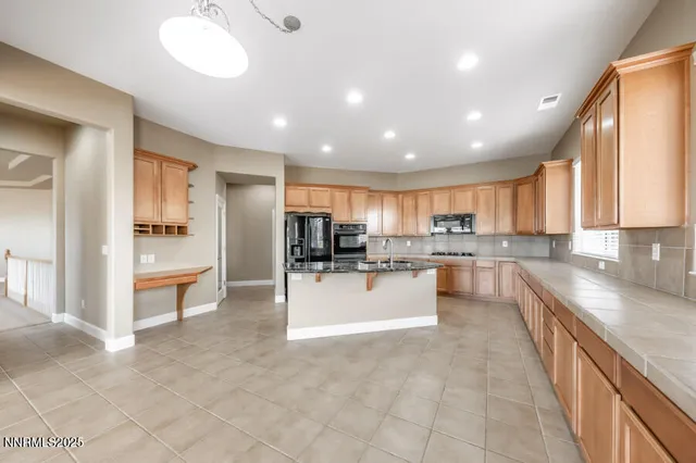 a large kitchen with kitchen island a sink a counter top stainless steel appliances and cabinets