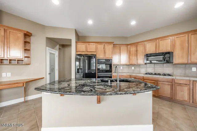 a kitchen with kitchen island granite countertop a stove top oven a sink a counter space and cabinets