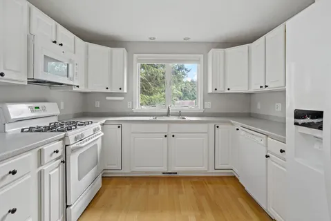 a kitchen with cabinets appliances a sink and a window