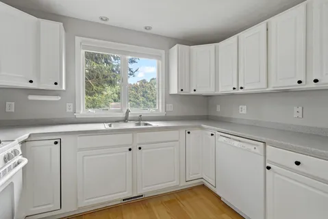 a kitchen with cabinets appliances a sink and a window