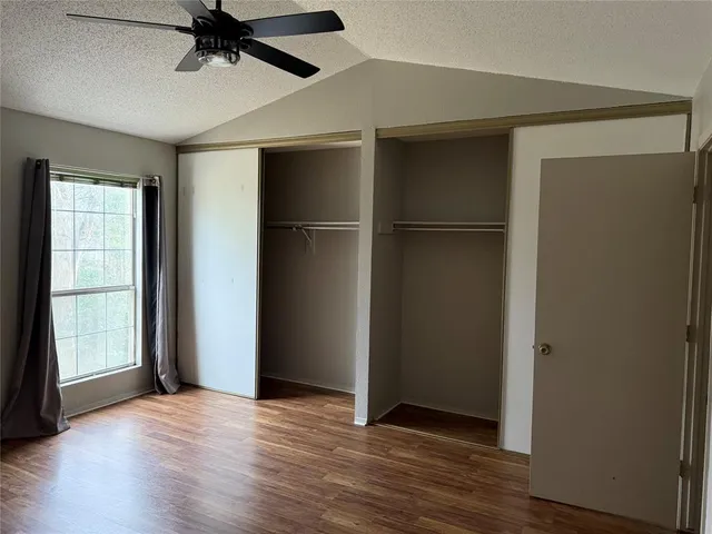 an empty room with wooden floor closet and windows