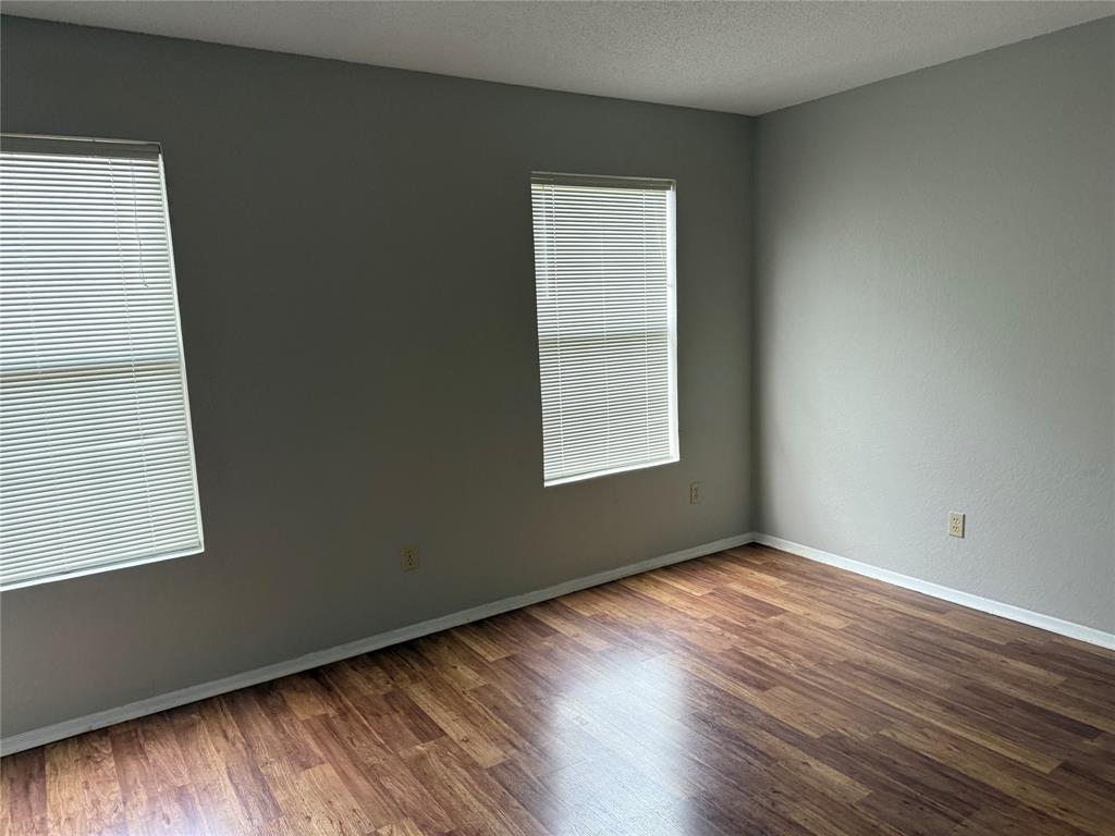 167 Merlin Way Euless, TX 76039 - Photo 9 of 18 an empty room with wooden floor and windows