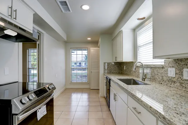 a kitchen with granite countertop a stove sink and cabinets