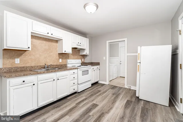 a kitchen with granite countertop a sink cabinets and wooden floor