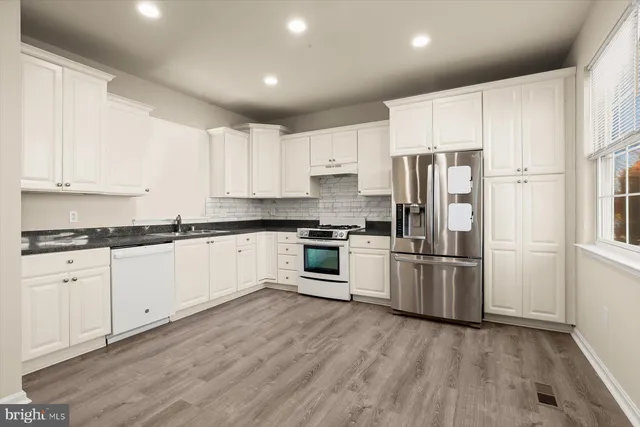 a kitchen with granite countertop white cabinets and stainless steel appliances