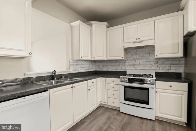 a kitchen with granite countertop white cabinets and white appliances