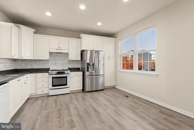 a kitchen with granite countertop white cabinets and stainless steel appliances