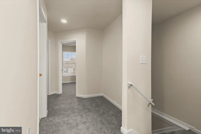 a view of a hallway with white walls and stairs