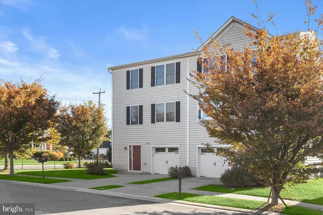 a view of a white house with a yard and large tree