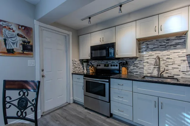 a kitchen with granite countertop stainless steel appliances a sink stove and cabinets