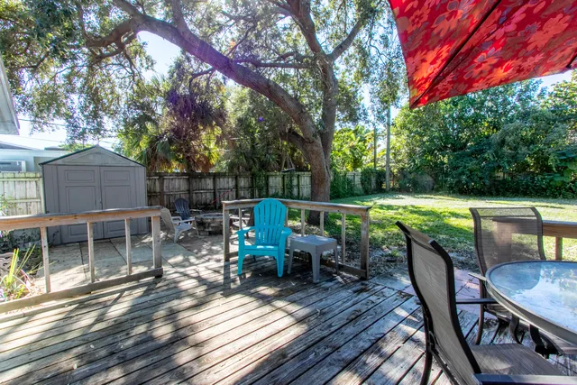 a view of a backyard with table and chairs potted plants and a large tree