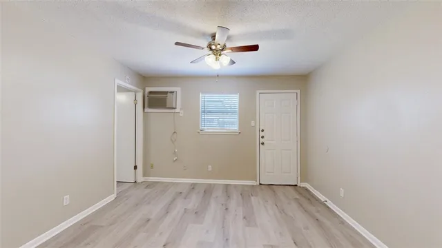 an empty room with wooden floor ceiling fan and windows