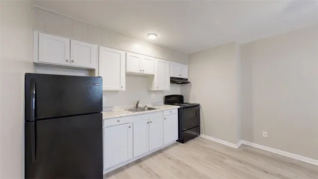 a kitchen with a sink a refrigerator and cabinets