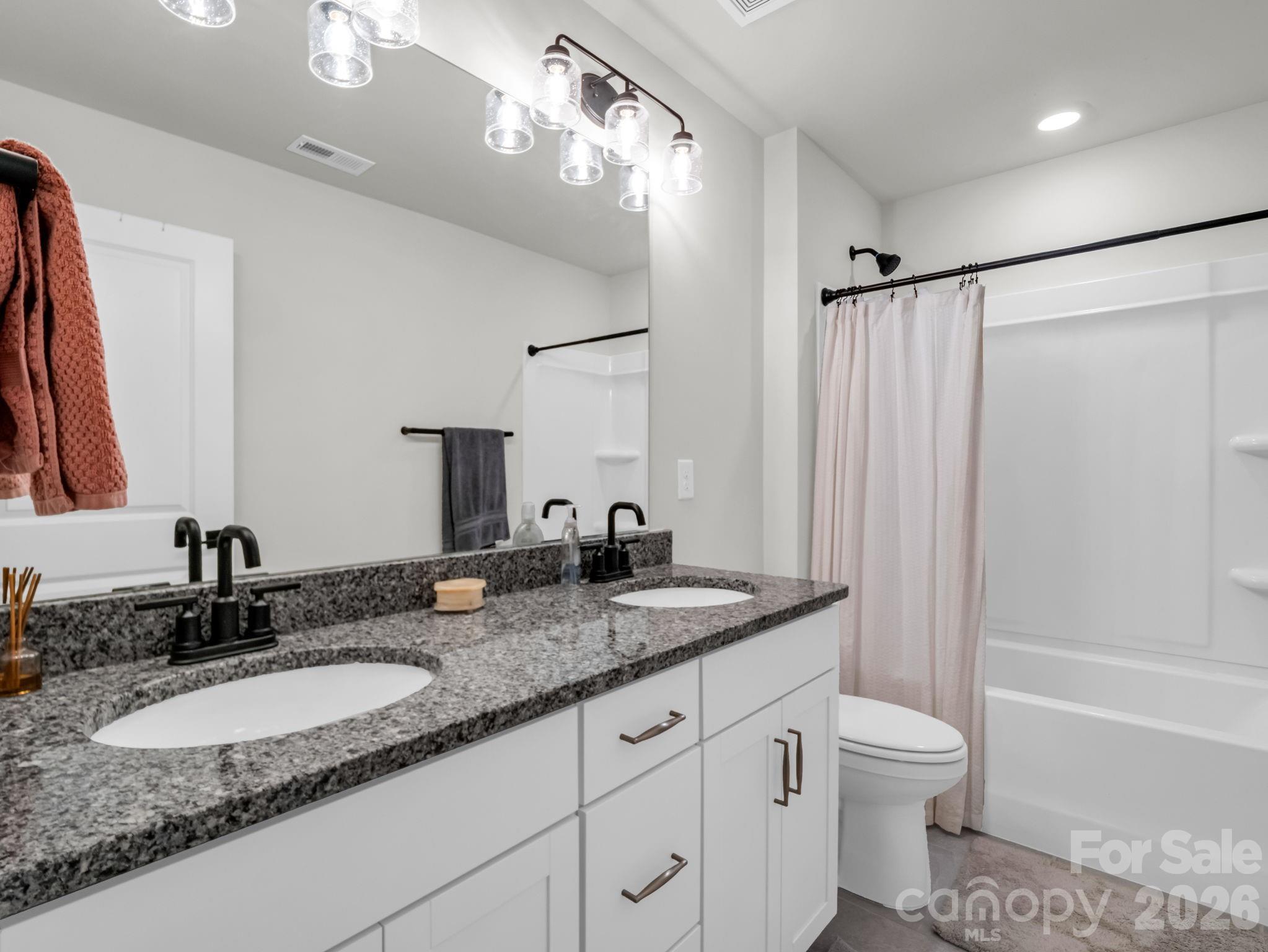 383 Fox Cove Road Hendersonville, NC 28792 - Photo 24 of 34 a bathroom with a granite countertop sink a toilet a mirror a vanity a bathtub and shower