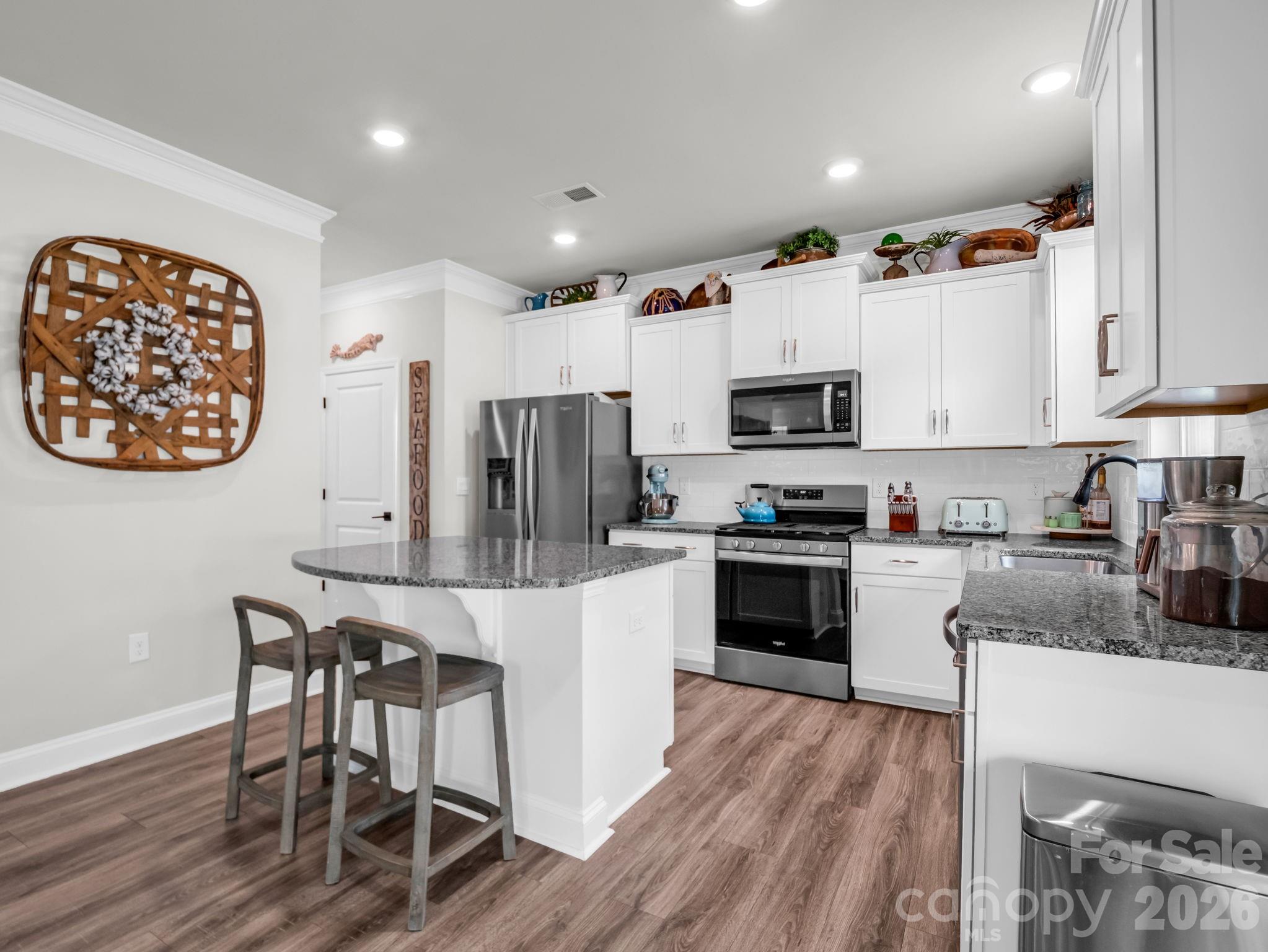 383 Fox Cove Road Hendersonville, NC 28792 - Photo 9 of 34 a kitchen with granite countertop a stove top oven a sink dishwasher a dining table and chairs with wooden floor