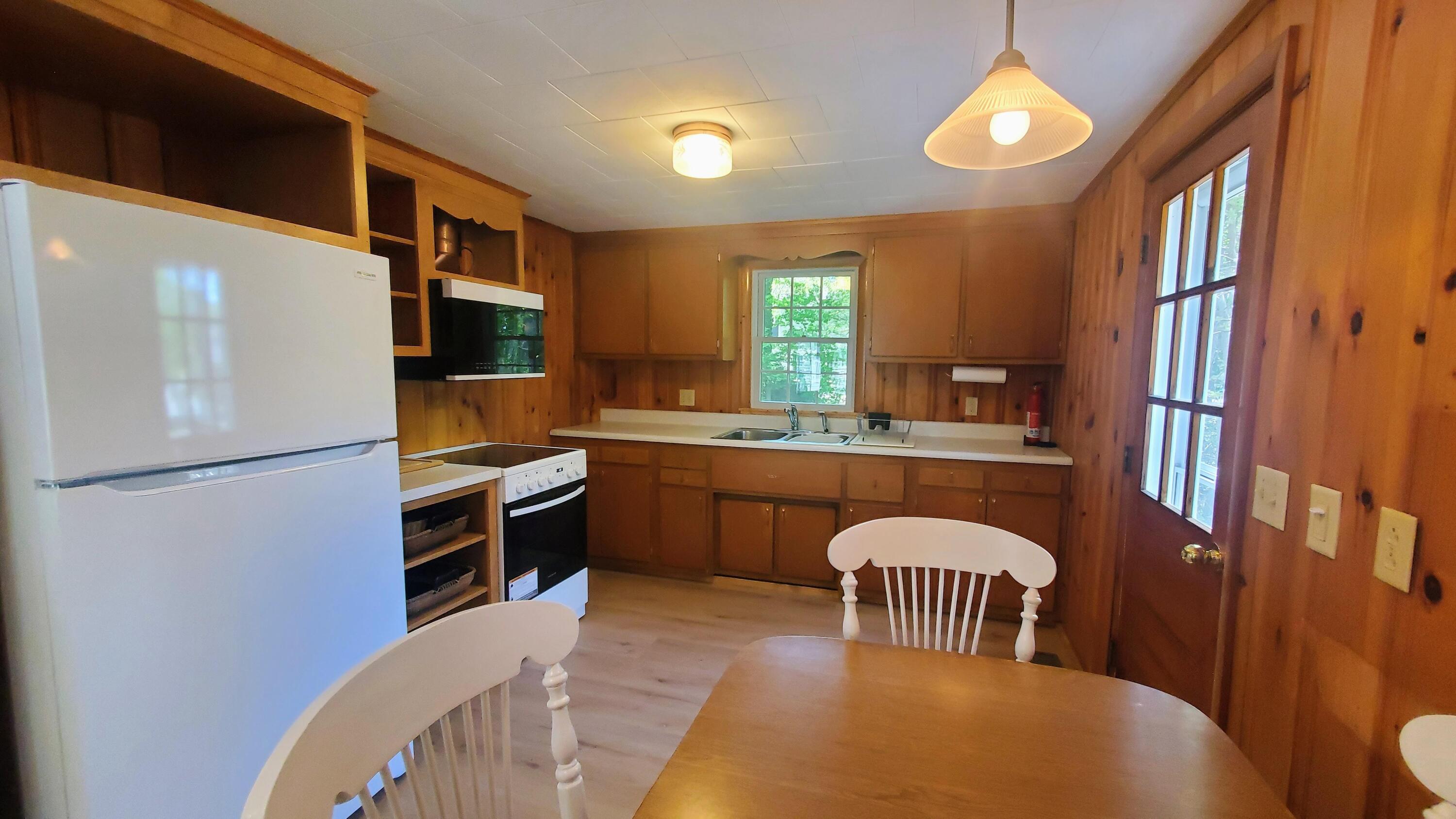 66 Uncle Edwards Road Mashpee, MA 02649 - Photo 5 of 18 a kitchen with a refrigerator a sink dishwasher a stove and a dining table with wooden floor