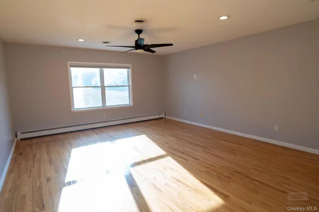 an empty room with wooden floor chandelier and windows