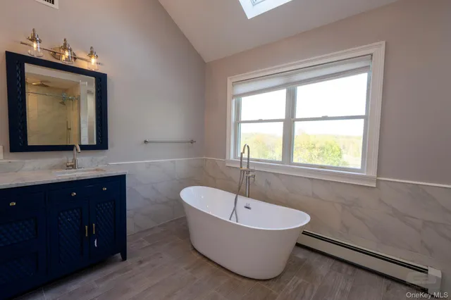 a bathroom with a bathtub a mirror a sink and window