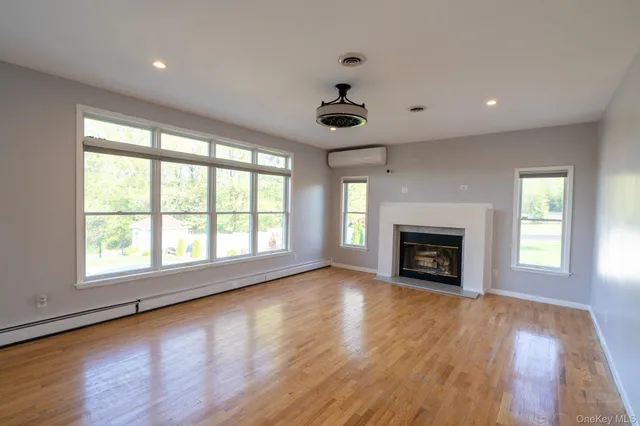 an empty room with windows fireplace and wooden floor
