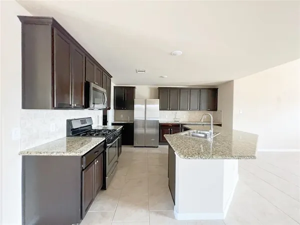 a kitchen with stainless steel appliances granite countertop a sink stove and microwave