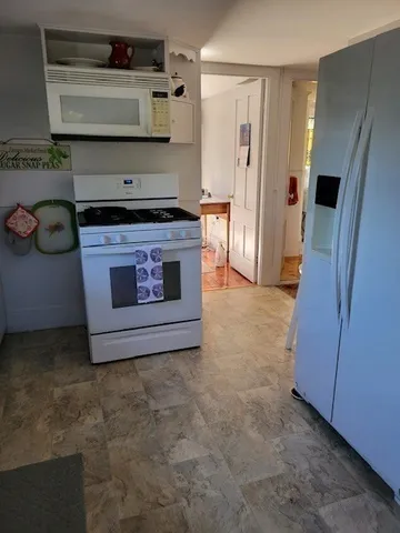 a view of a kitchen with fridge and wooden floor
