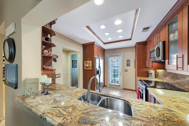 a kitchen with stainless steel appliances granite countertop a sink and a refrigerator