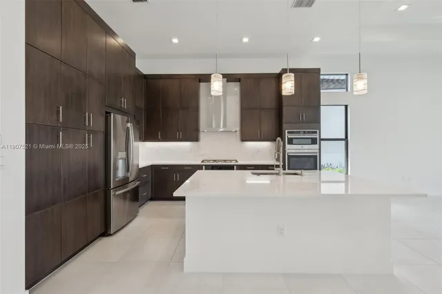 a large kitchen with stainless steel appliances kitchen island a large counter top and wooden cabinets