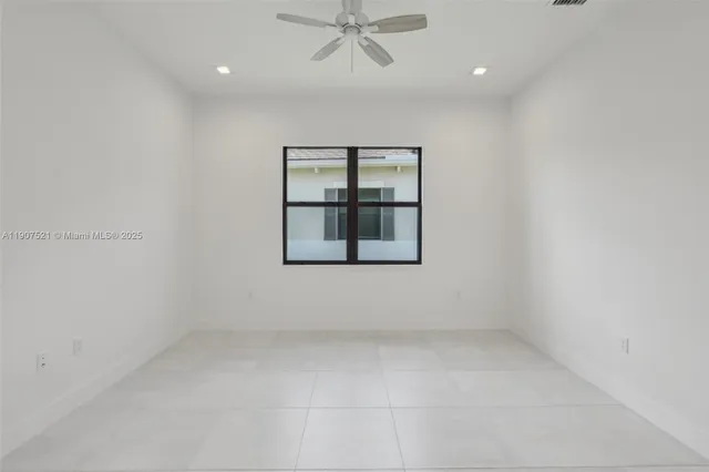 an empty room with a window and ceiling fan