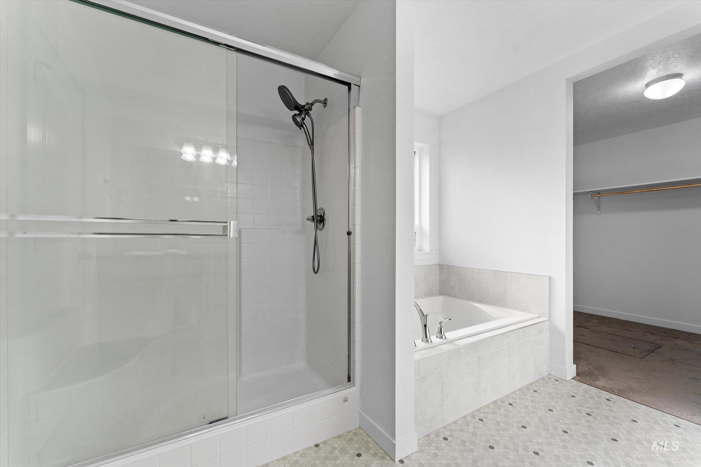 17798 Goose Ridge Avenue Nampa, ID 83687 - Photo 15 of 31 Full bathroom with a garden tub, a spacious closet, a stall shower, tile patterned floors, and a textured ceiling