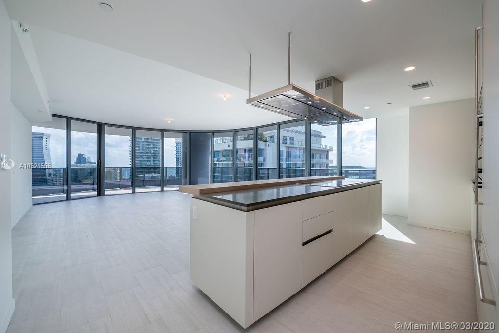 a large kitchen with stainless steel appliances wooden floor and a large window