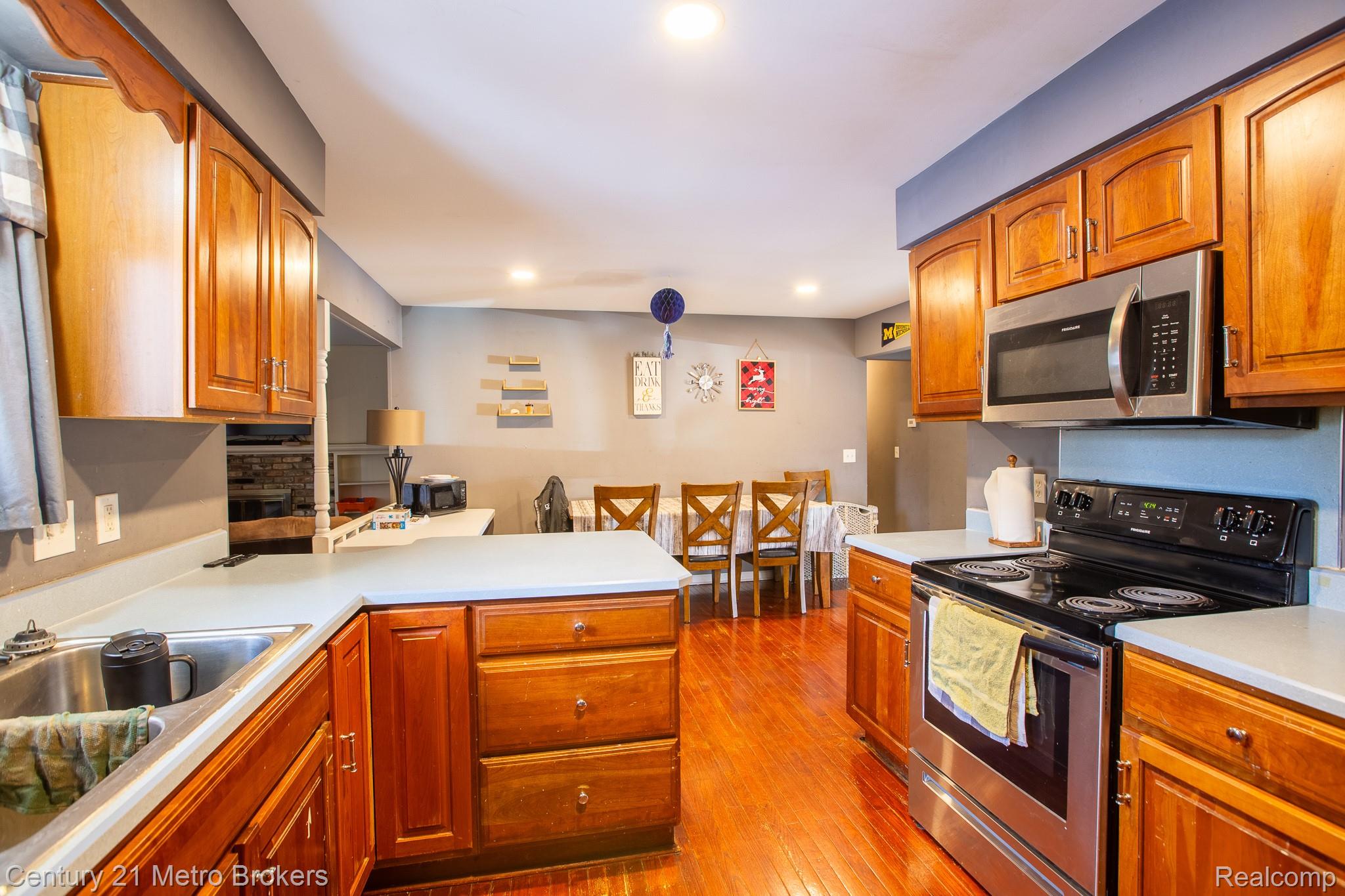 6101 Belsay Road Grand Blanc, MI 48439 - Photo 14 of 28 Kitchen featuring stainless steel electric range, wood finish cabinets, light countertops, dark wood finished floors, and a peninsula