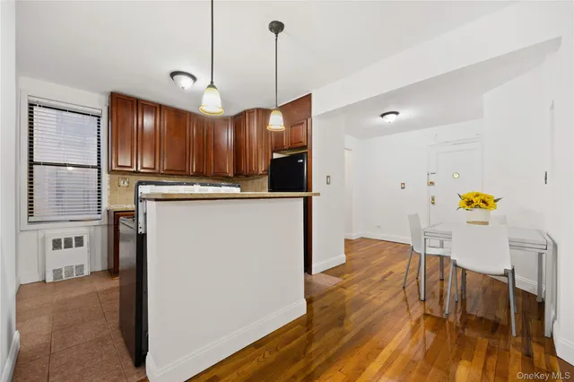 a kitchen with stainless steel appliances granite countertop a refrigerator a sink dishwasher a stove and a dining table with wooden floor