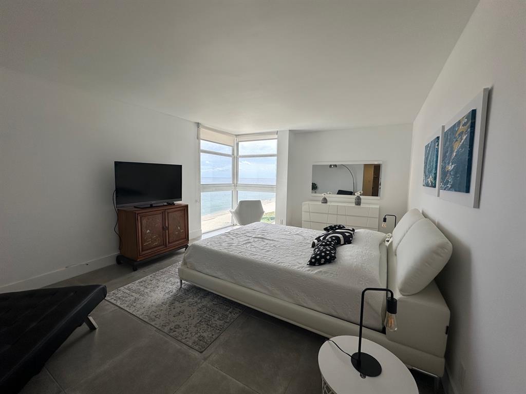 1370 South Ocean Boulevard, Unit 902 Pompano Beach, FL 33062 - Photo 4 of 21 a bedroom with a bed window and a flat screen tv