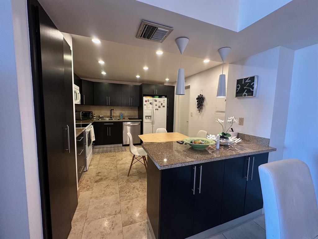1370 South Ocean Boulevard, Unit 902 Pompano Beach, FL 33062 - Photo 8 of 21 a kitchen with kitchen island granite countertop a sink and counter space