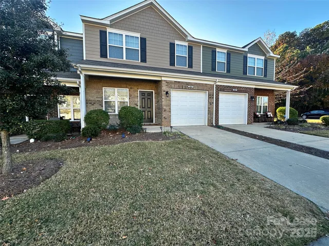 a front view of a house with yard and parking