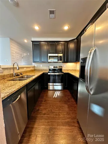 a kitchen with stainless steel appliances granite countertop a sink stove and refrigerator