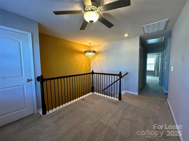 a view of a hallway with a chandelier fan and windows