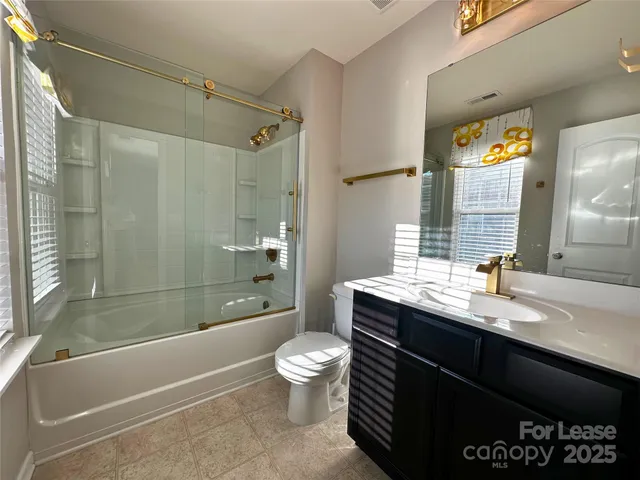 a bathroom with a granite countertop bathtub sink vanity mirror and toilet